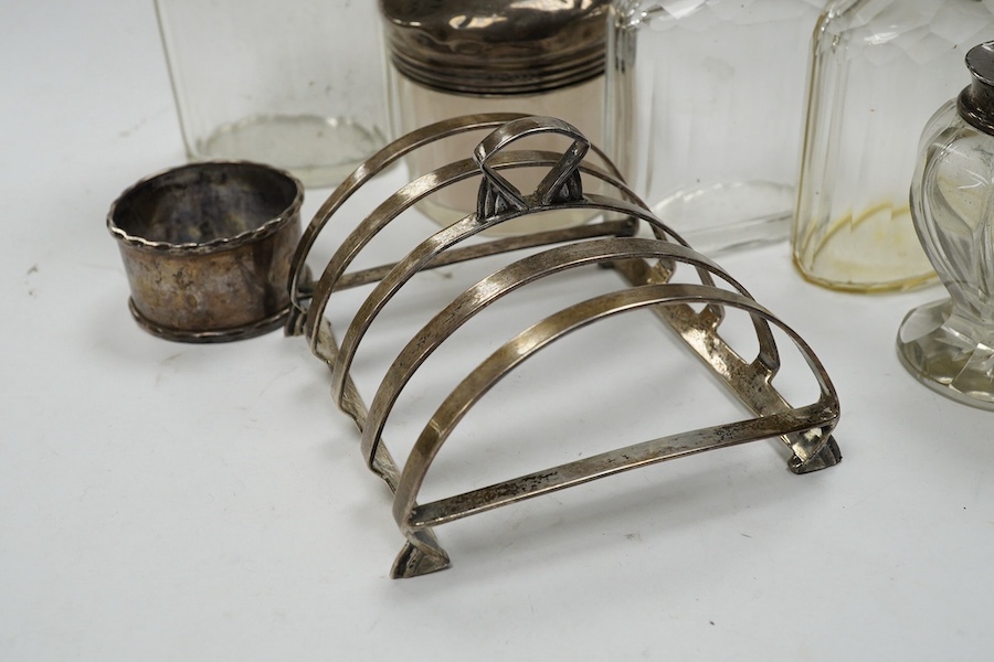 An Art Deco silver five bar toast rack by Charles S. Green & Co Ltd, Birmingham, 1935, 9cm, a silver napkin ring and six assorted silver topped glass toilet bottles. Condition - poor to fair